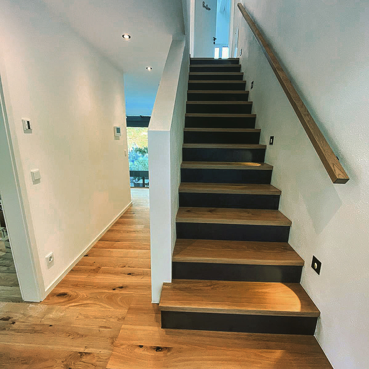 Moderne Treppe mit Holzstufen und dunklen Setzstufen